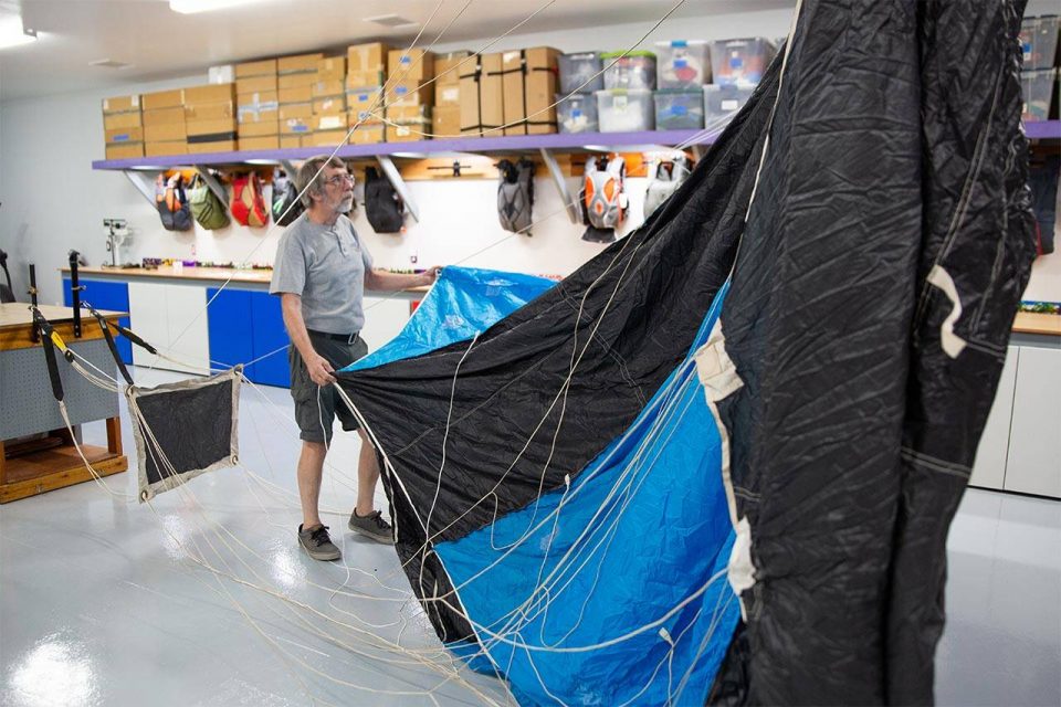 FAA Master Rigger Sandy Reid unfurling a large black and blue parachute canopy