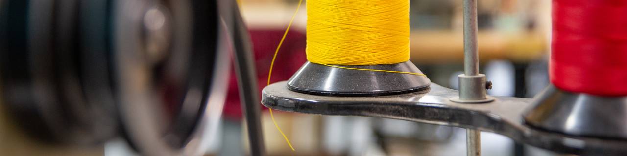 Spools of yellow and red string on a sewing machine